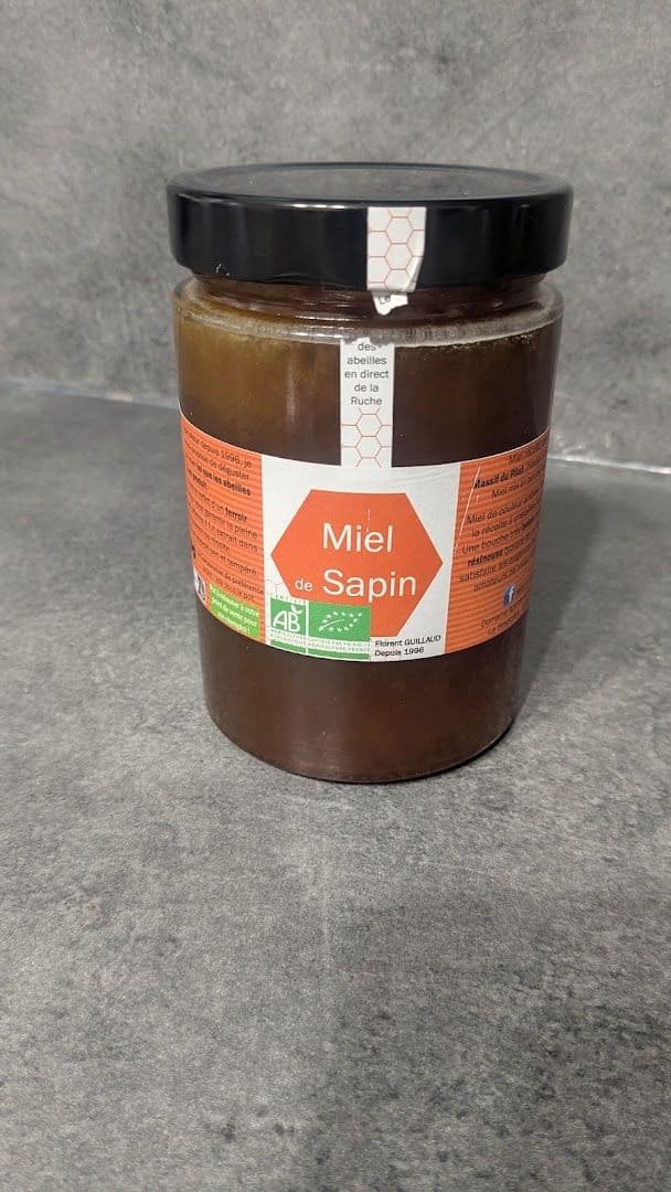 Un pot de miel de sapin à l'étiquette orange Miel et Plus.